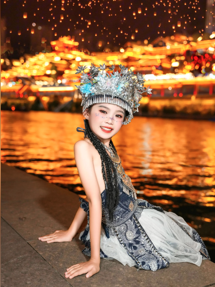 宣恩大桥下的拍照点位：身着苗银盛装的旅拍写真，背景为贡水河夜景